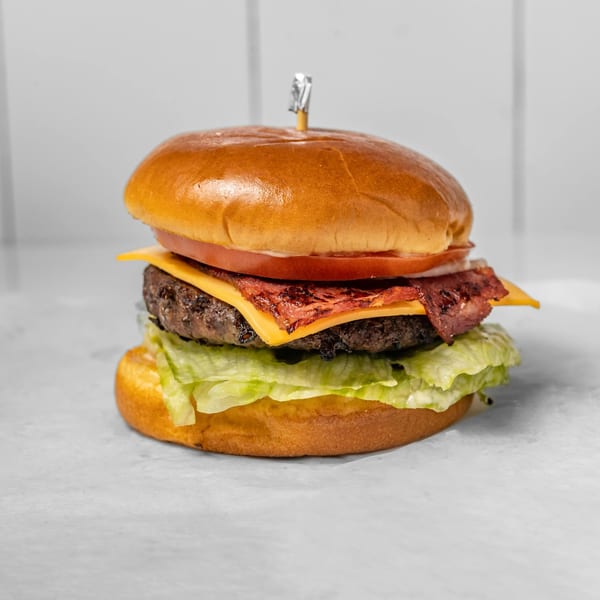 A Zamzam Halal burger with a beef patty, cheese, bacon, tomato, onion, and lettuce.