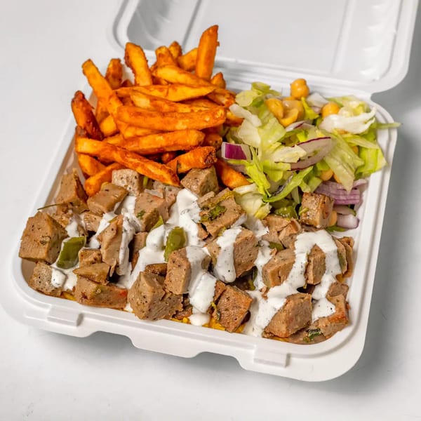 Halal chicken and rice platter with white sauce, fries, and salad in a takeout container.