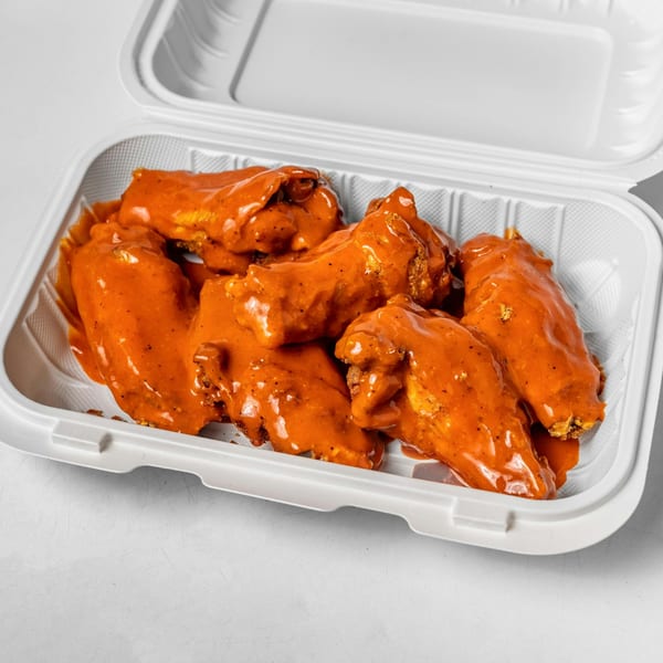 Several Zamzam Halal chicken wings, coated in a vibrant orange sauce, are presented in a white takeout container.