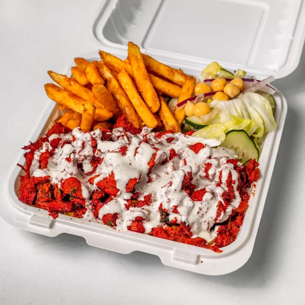 Halal chicken tikka with white sauce, fries, and salad in a white takeout container.