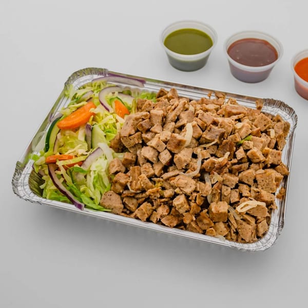 Halal chicken and salad in a foil container with three small sauce cups on the side.